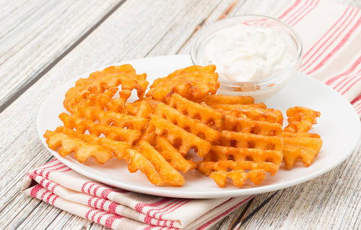 Potato waffle fries with a sour cream and chive dip - studio shot