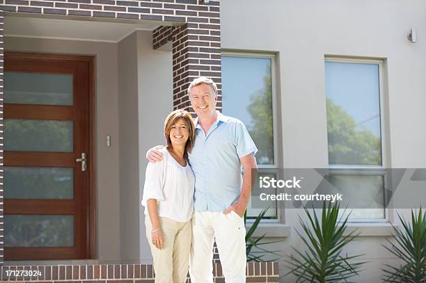 Mature Couple Standing In Front Of A Modern House Stock Photo - Download Image Now - In Front Of, House, Mature Couple