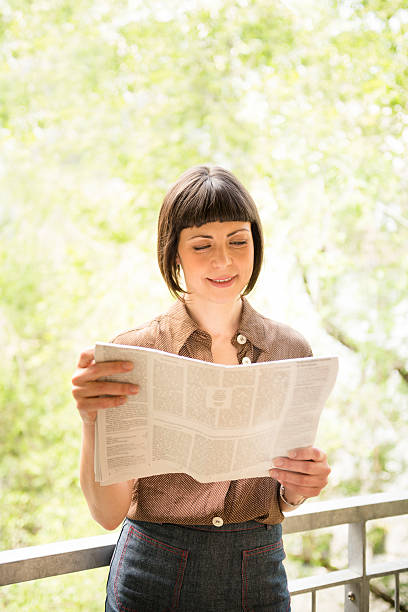 istock Smiling woman reading a newspaper 171273053