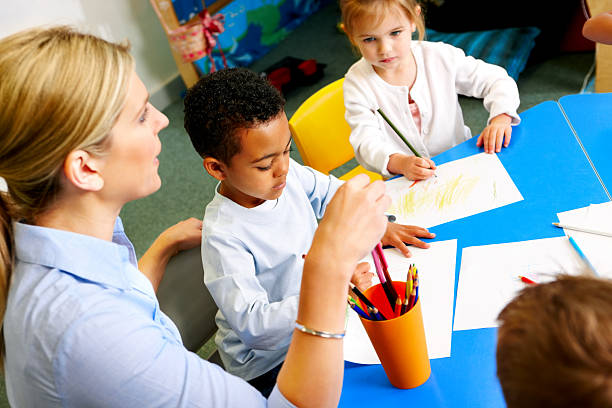 istock Helpful young teacher with preschoolers in class room 171273322