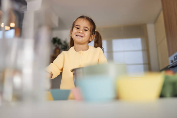 Young girl stands at the kitchen table making cakes.