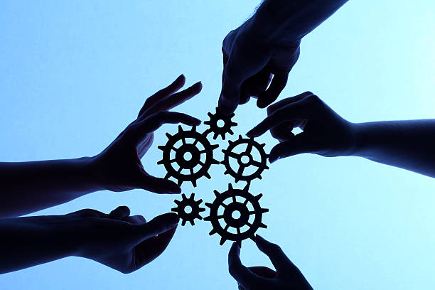Silhouette of hands holding cogs and gears stock photo