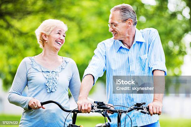 Foto de Alegre Casal Andando De Bicicletas No Parque e mais fotos de stock de Adulto - Adulto, Adulto maduro, Alegria