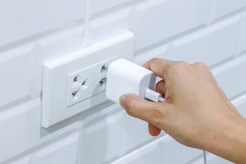 Hand holding to connect USB type c adaptor plug into electrical wall outlet, Electrical equipment, Connect the charger connector to household power. Energy saving concept.