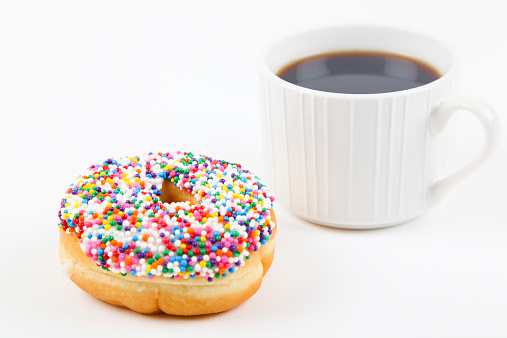 Sugar donut with a cup of coffee on the white background.