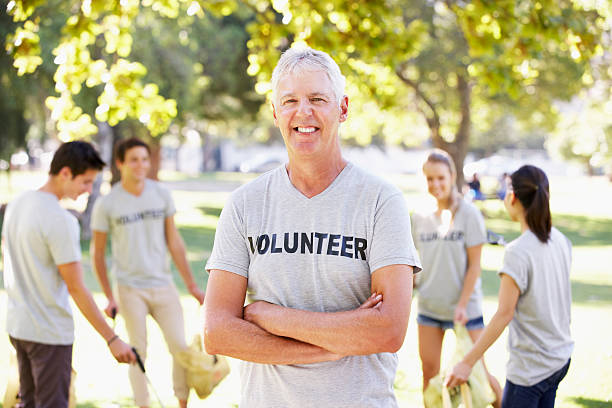 Volunteer Group Clearing Litter In Park Wearing Vounteer T Shirt Smiling
