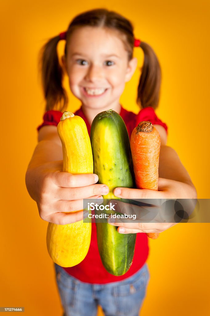 Chica joven sonriente sostiene amarillo Squash, pepino y zanahoria - Foto de stock de 6-7 años libre de derechos
