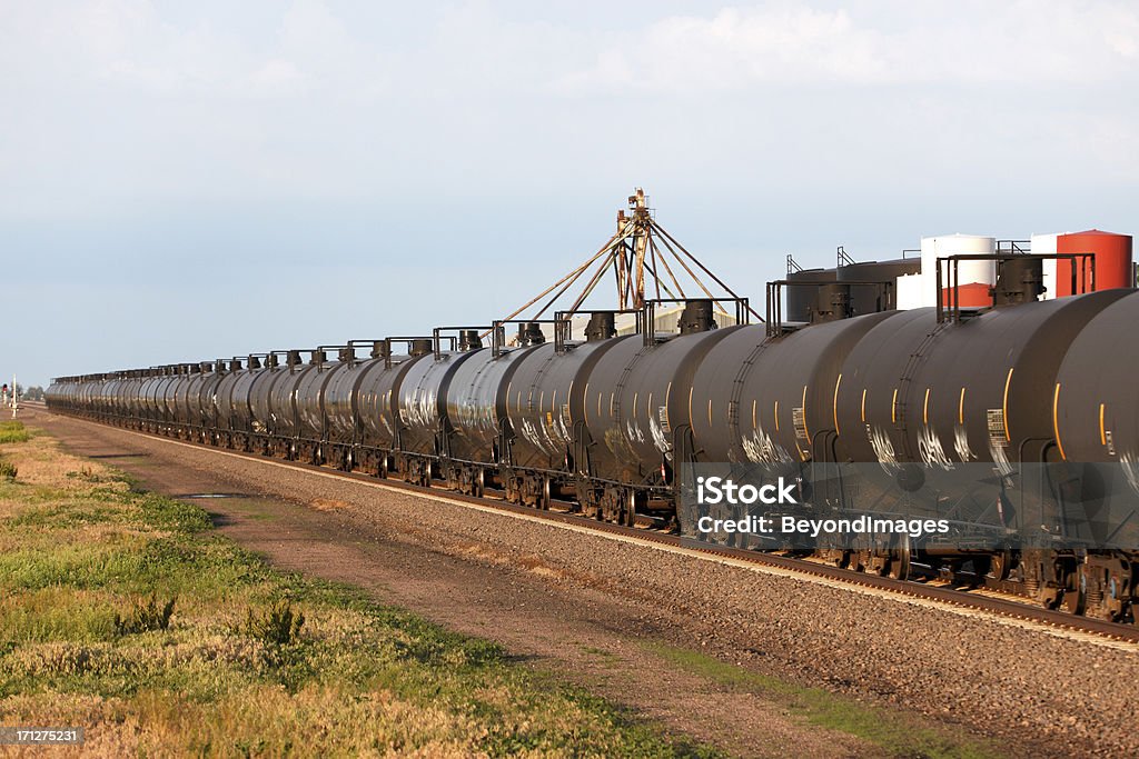 Moving oil pipeline - railroad cars passing industrial site A long line of railroad oil tank cars (oil pots) race past an industrial plant.  Mobile oil pipeline on wheels.  Passing left to right.  Copy space. Kearney County Stock Photo