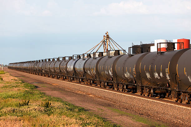 Moving oil pipeline - railroad cars passing industrial site A long line of railroad oil tank cars (oil pots) race past an industrial plant.  Mobile oil pipeline on wheels.  Passing left to right.  Copy space. kearney county stock pictures, royalty-free photos & images