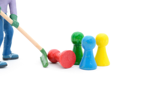Figurine sweeps away board game pieces on white background