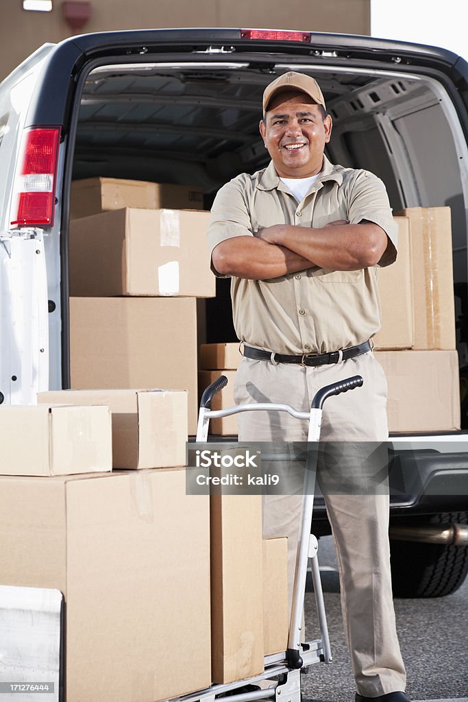 Hispanic man delivering packages Hispanic man (40s) with delivery van full of cardboard boxes. Parking Lot Stock Photo