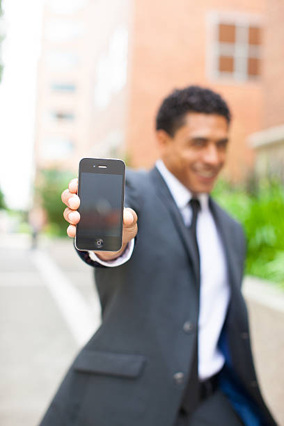 Businessman with futuristic smartphone sending message