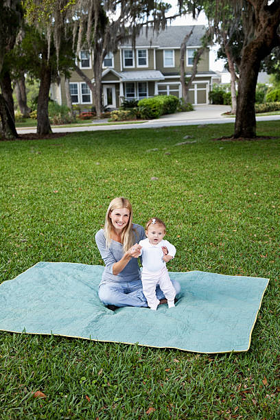 Mother (30s) with baby girl (7 months) on blanket in yard.