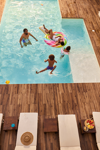 High angle view of happy African American family enjoying while spending a summer day in the swimming pool. Copy space.