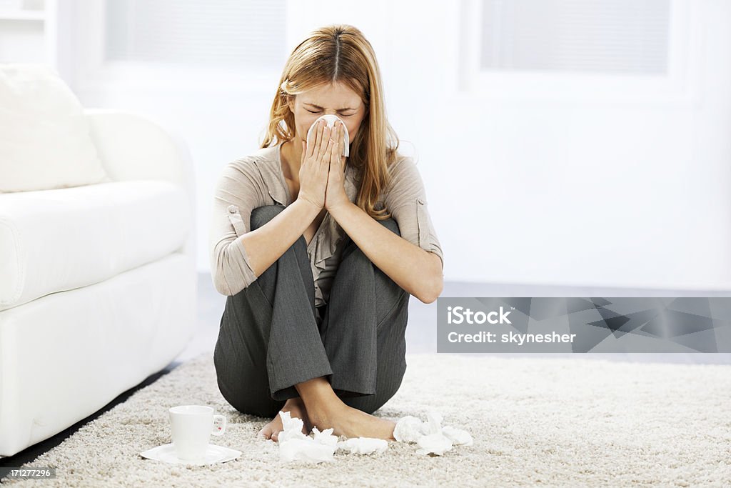 Young woman having a flu. Young woman blowing her nose. Unpleasant Smell Stock Photo