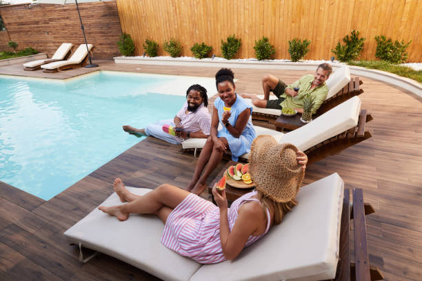 Happy diverse friends talking during social gathering by the pool. Group of happy diverse friends communicating while enjoying in summer day by the swimming pool. Copy space. black man eating watermelon stock pictures, royalty-free photos & images