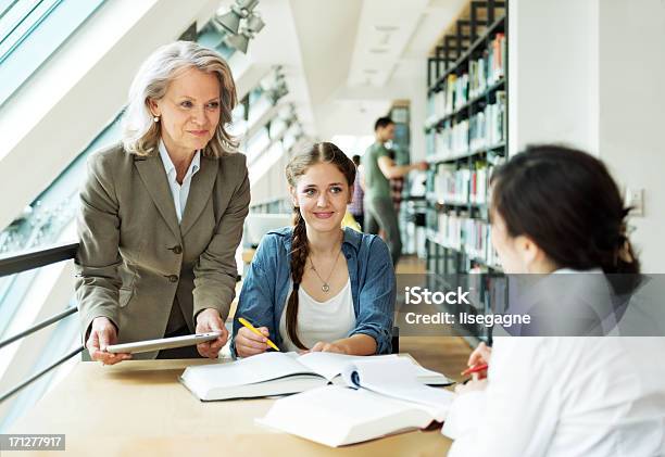 Profesor Y Estudiante Foto de stock y más banco de imágenes de Ayuda - Ayuda, Biblioteca, Estudiante de secundaria