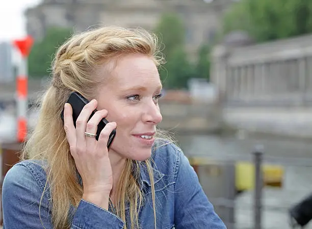 A young blond women speaking on her mobile phone.