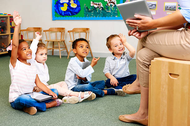istock Teacher in class showing digital tablet PC with students volunteering 171278518