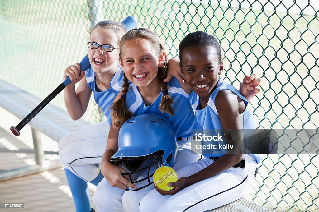 Niñas de softball equipo de estar en el banquillo de campo de béisbol - Foto de stock de Niño libre de derechos