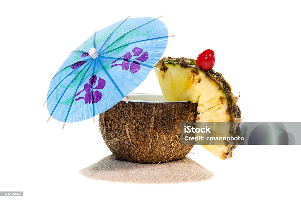 Tropical Coconut Drink "Tropical Coconut Drink with an umbrella, pineapple slice and cherry sitting in sand against a white background" Coconut Stock Photo