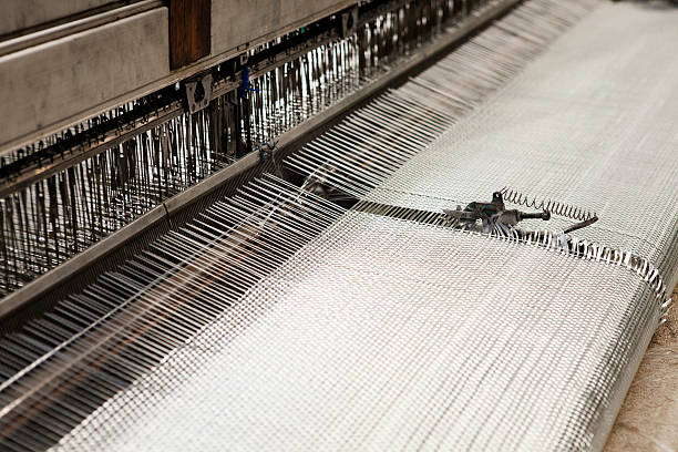 Fibreglass weave Close-up view of a working fibreglass weave machine in a factory fibreglass stock pictures, royalty-free photos & images