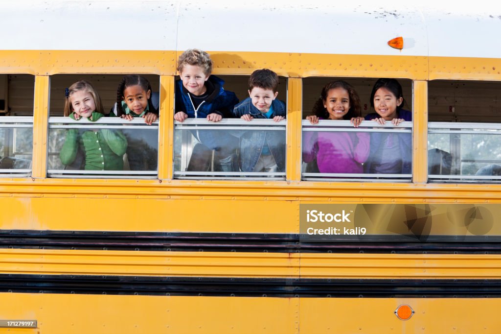 Young children poking heads out school bus windows "Multi-ethnic elementary school students (5 to 9 years) in school bus, looking out windows." Child Stock Photo