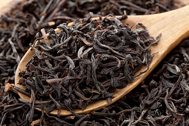Black tea Black tea photographed in wooden spoon tea leaves stock pictures, royalty-free photos & images