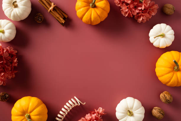 istock Autumn frame with pumpkins, flowers, fall decor on dark red background. 1712801115