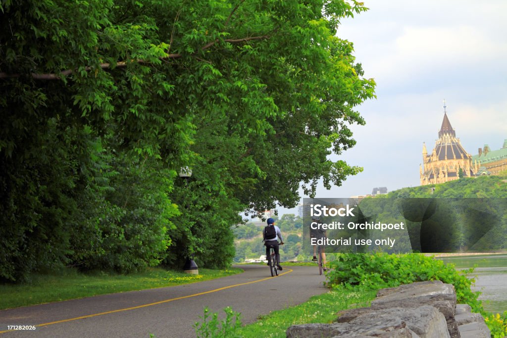 Scenic Cycling Path "Gatineau, Canada - June 19, 2012: Two cyclists riding along the scenic cycling path with Parliament Hill in Ottawa in the background" Ottawa Stock Photo