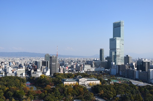 Osaka, Japan – November 12, 2022: This image captures a stunning aerial view of a bustling city skyline featuring tall, majestic skyscrapers against a clear blue sky