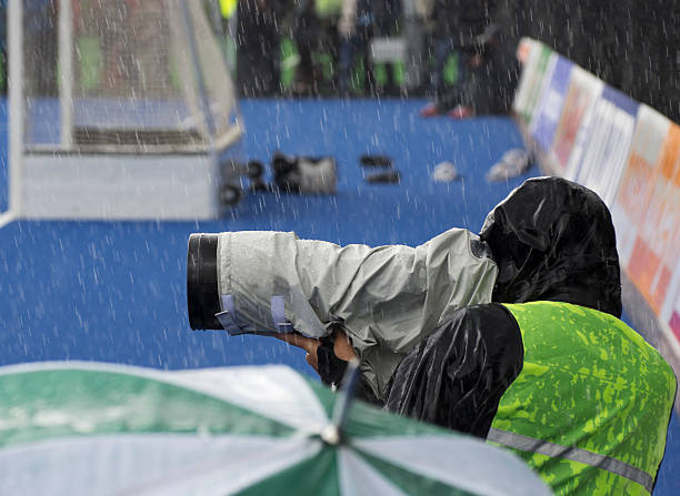 Sports photographer at work in rain A sports photographer at work in rain sports photography stock pictures, royalty-free photos & images