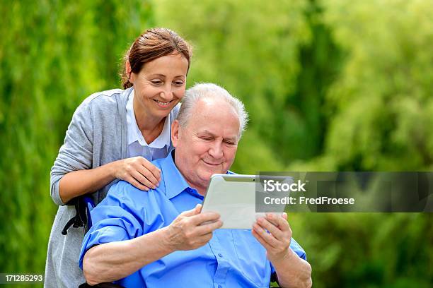 Uomo Anziano Seduto Su Una Sedia A Rotelle Con Il Caregiver - Fotografie stock e altre immagini di Assistente domiciliare