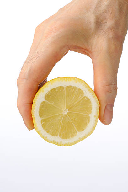 istock Holding a cross section of lemon against white background 171285341