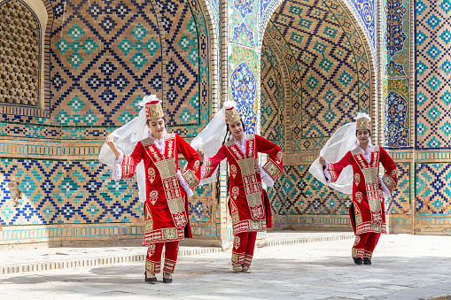 Uzbek female folk dancers in red national clothes. Travelling and culture. April 20, 2023 - Bukhara, Uzbekistan