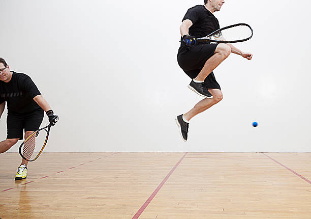 Racquetball Jump Two men playing racquetball on court. Shot at 1/100 of a second shutter speed to create a slight blurred motion to reveal the fast motion of racquetball. racketball stock pictures, royalty-free photos & images