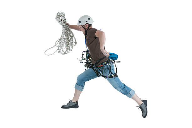 fully equipped The hipster-climber is standing in a down jacket and rock shoes on a high rock with a rope on his shoulder and carbines on his belt. The concept of extreme rest in the mountains
