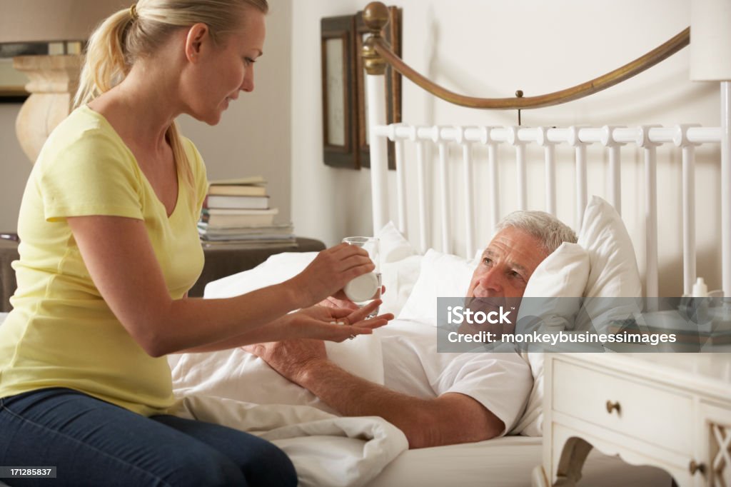 Hija adulta Senior hombre dando medicamento original en la cama - Foto de stock de Tercera edad libre de derechos