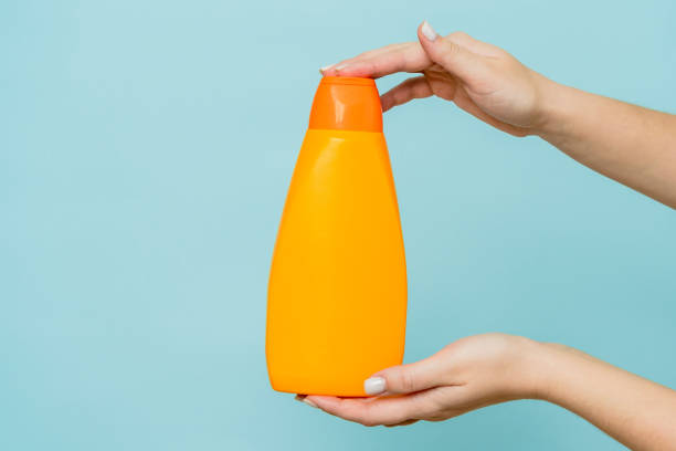 istock Woman's hand holding packaging of shampoo or conditioner on blue background. Copy space and mock up 1712859542