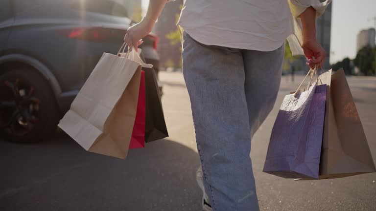 Woman walking on asphalt road with shopping bags in hands