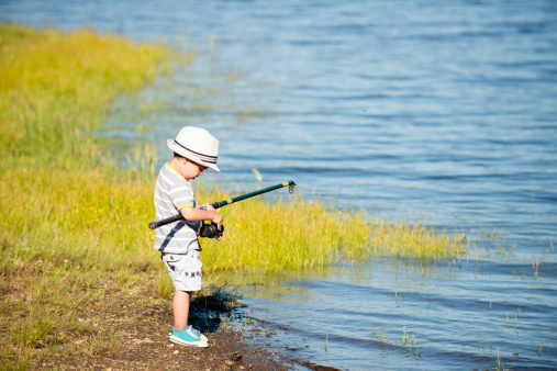 Little boy on a lake, struggling with fishing rod