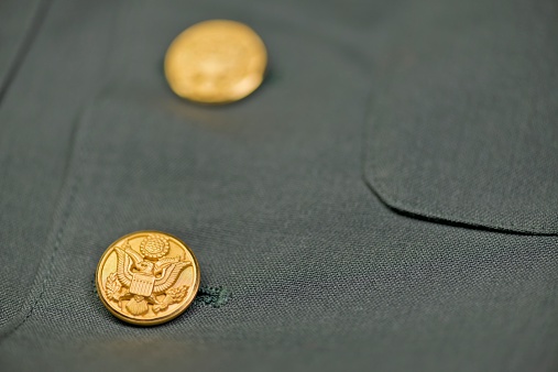 Close up view of the buttons on a US Army dress jacket from the Vietnam era.  The gold or brass US eagle buttons stand out against the green uniform.