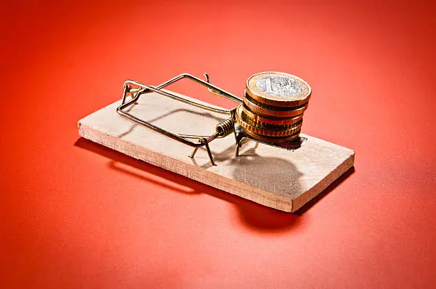 "Mousetrap with Euro coins, isolated on red background, vignetting."