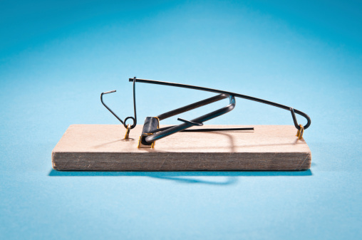Single wooden mousetrap isolated on blue, side view, studio shot.