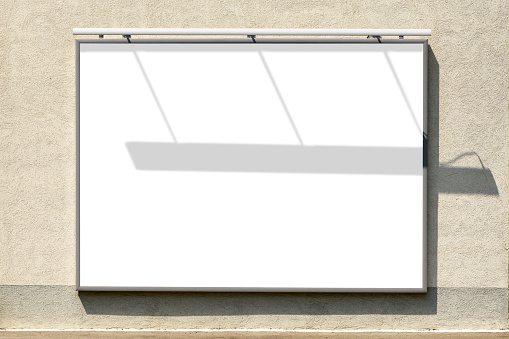 Billboard mockup. Blank advertising poster in frame mounted on building exterior wall with shadow effect. No people.