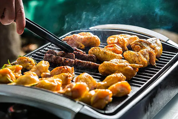 Barbeque electric grill with cevapcici and chicken wings.
