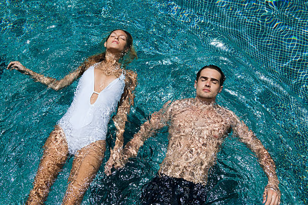 couple à la piscine - floating on water swimming pool men water photos et images de collection