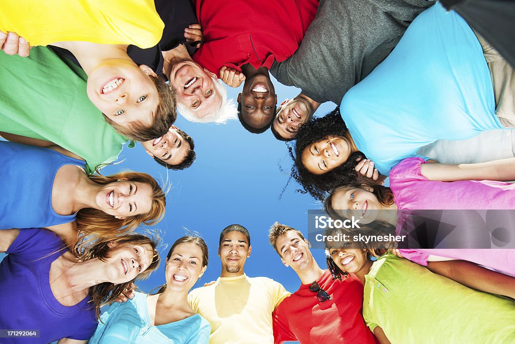 Gruppo di persone in cerchio capofitto in piedi contro il cielo azzurro. - Foto stock royalty-free di Bambino