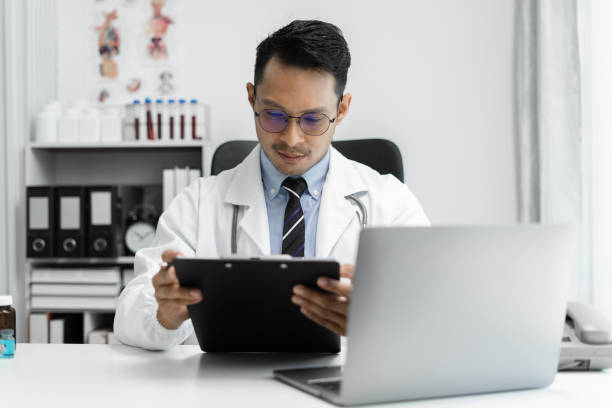 istock Doctor working on laptop computer, writing prescription clipboard with record information paper folders on desk in clinic, Healthcare and medical concept. 1712920720