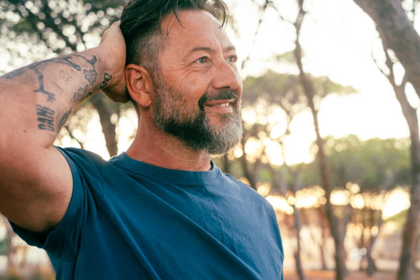 istock One man outdoor with serene happy expression on face touching his head and looking nature around. Mature people in summer outdoor leisure activity with trees and sunset in background. Life balance 1712922535